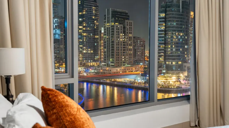 Night view of Dubai Marina towers and waterway seen through a hotel room window