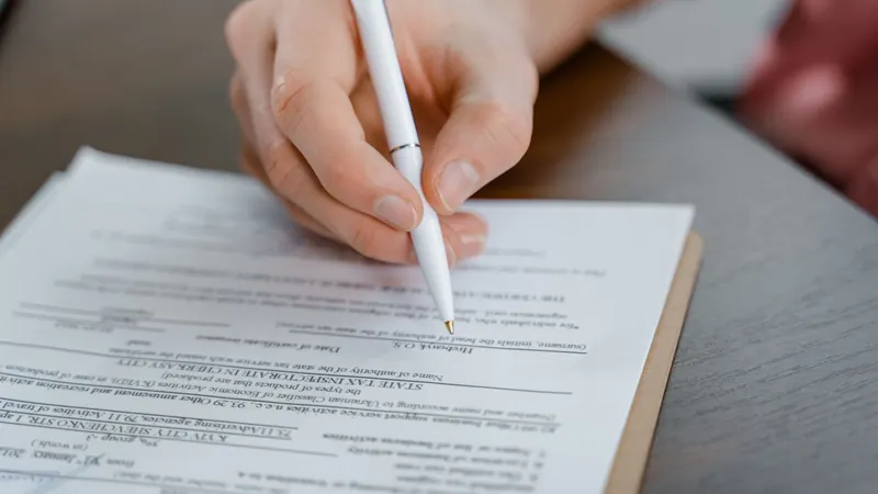 Close-up of a hand holding a pen while signing a document