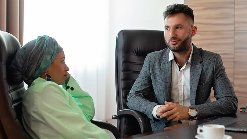 A woman and a man seated at a desk during a business consultation