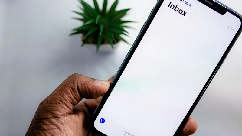 Hand holding a smartphone showing an email inbox